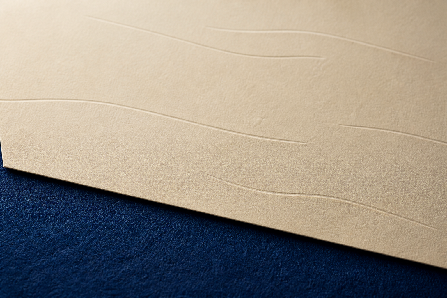 Durchgehende cremefarbene Papierfläche mit wenigen langen unregelmäßigen Blindrillen auf tiefblauem Filz